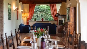 A dining area with a long table set for a meal, surrounded by wooden chairs.