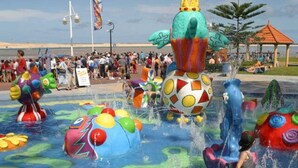 A water park with various colorful water features and a crowd of people.