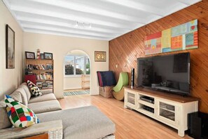 A living room with a sofa, TV, bookshelf, and a wooden wall. - GoneToTheBeach - Beach, Spa, Pool table, Pets, Boards, Rods, Bikes. 
 Awesome. (The Entrance North)