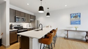 A modern kitchen with a central island, bar stools, a microwave, and a refrigerator. - 175 LEX - Walkable Downtown Lexington - Top Floor (Lexington)