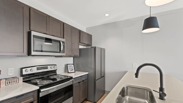 A modern kitchen with stainless steel appliances, a microwave, a refrigerator, and a sink. - 175 LEX - Walkable Downtown Lexington - Top Floor (Lexington)