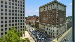 A city street with buildings, including a large brick building with multiple stories and a modern glass building. - 175 LEX - Walkable Downtown Lexington - Top Floor (Lexington)