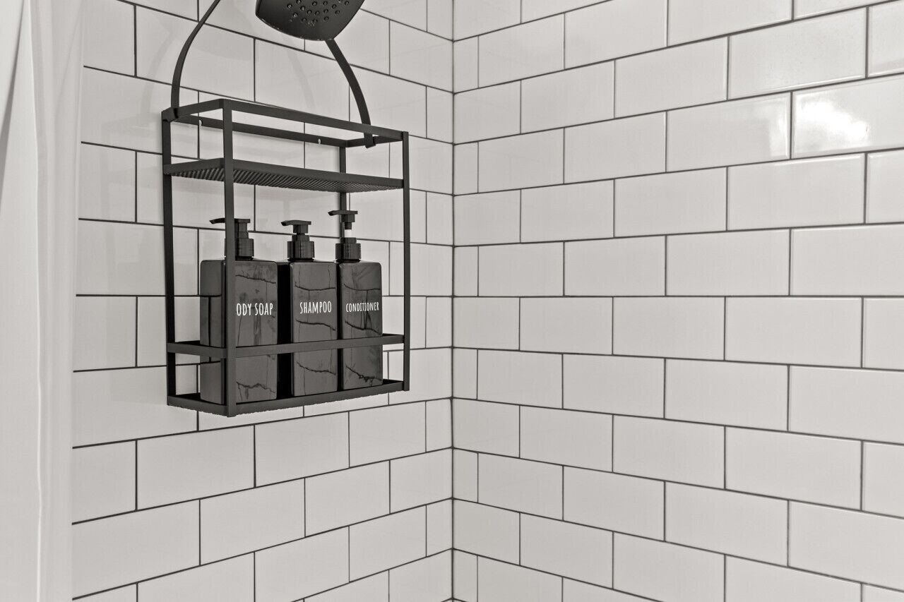 A bathroom with white tiled walls and a corner shower area.