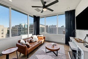Ein modernes Wohnzimmer mit einer Ledersofa, einem runden Couchtisch und einem großen Fenster mit Blick auf die Stadt.