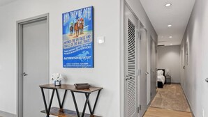 A hallway with a race track poster, a small table with a vase, and a bed in the distance. - 175 LEX - Loft in Downtown Lexington, Rupp Arena (Lexington)