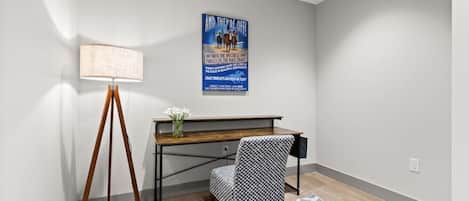 A room with a desk, a lamp, a chair, and a poster on the wall.