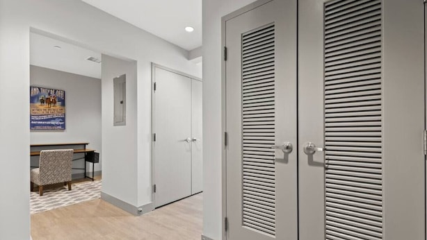 A hallway with two grey louvered doors, a bench, and a poster on the wall. - 175 LEX - Walkable Downtown Lexington Condo (Lexington)