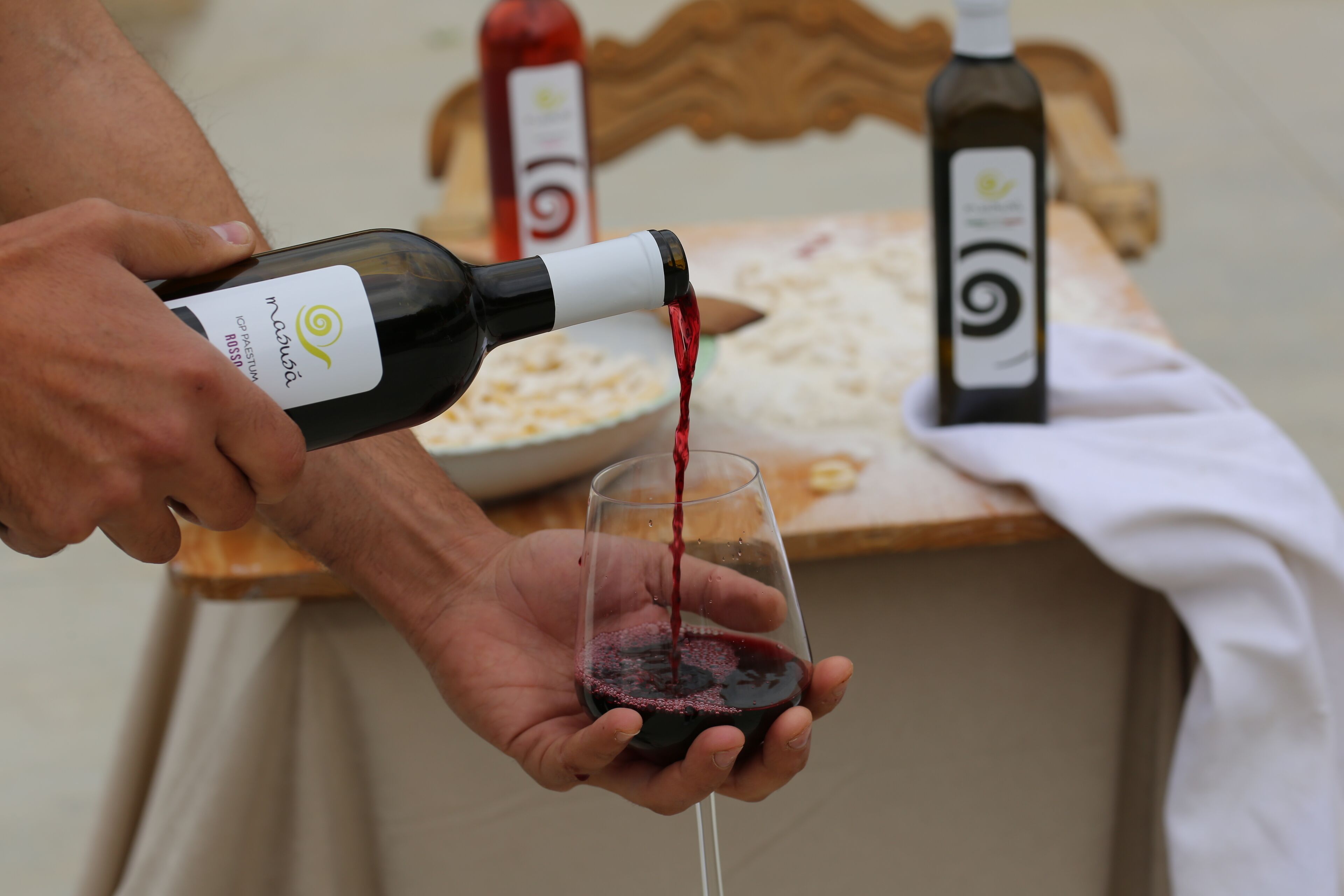 Una persona sirviendo vino tinto en una copa.