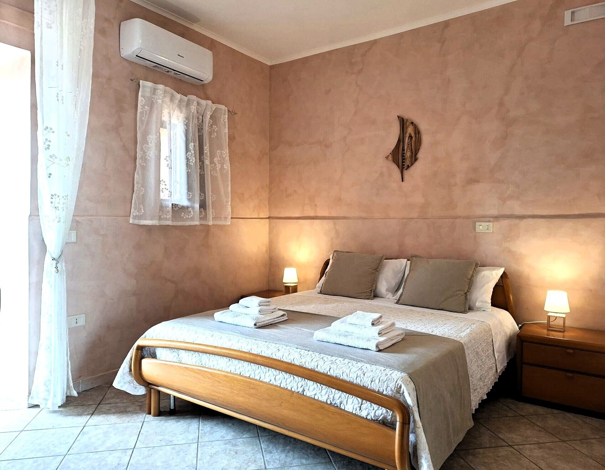 Une chambre à coucher comprenant un lit, des lampes de chevet, un appareil de climatisation et un élément décoratif fixé au mur.