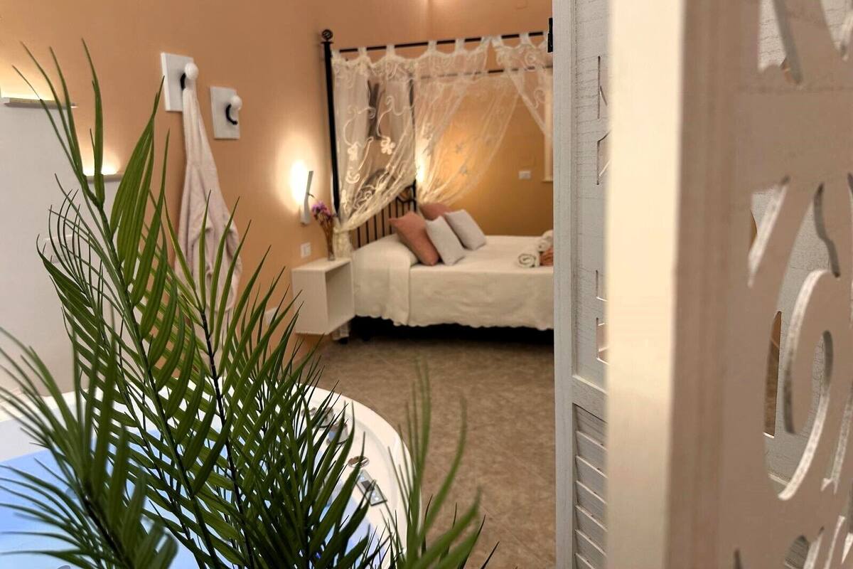 Une chambre à coucher avec un lit, une table de chevet, une lampe et une plante.