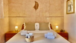 A hotel room with a large bed, two nightstands, a wall-mounted light fixture, and a framed picture on the wall. - Agri Resort Masusa (Aquara)