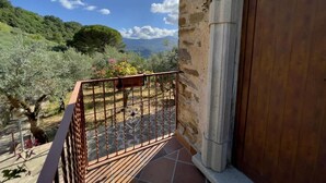 A balcony with a view of a mountainous landscape, a stone wall, and a wooden door. - Agri Resort Masusa (Aquara)