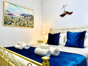 Une chambre d’hôtel avec un lit, des oreillers, un tableau et une paire de chaussures accrochées au mur.