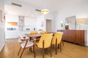 Una cocina moderna con armarios blancos, una mesa de comedor de madera y sillas amarillas.