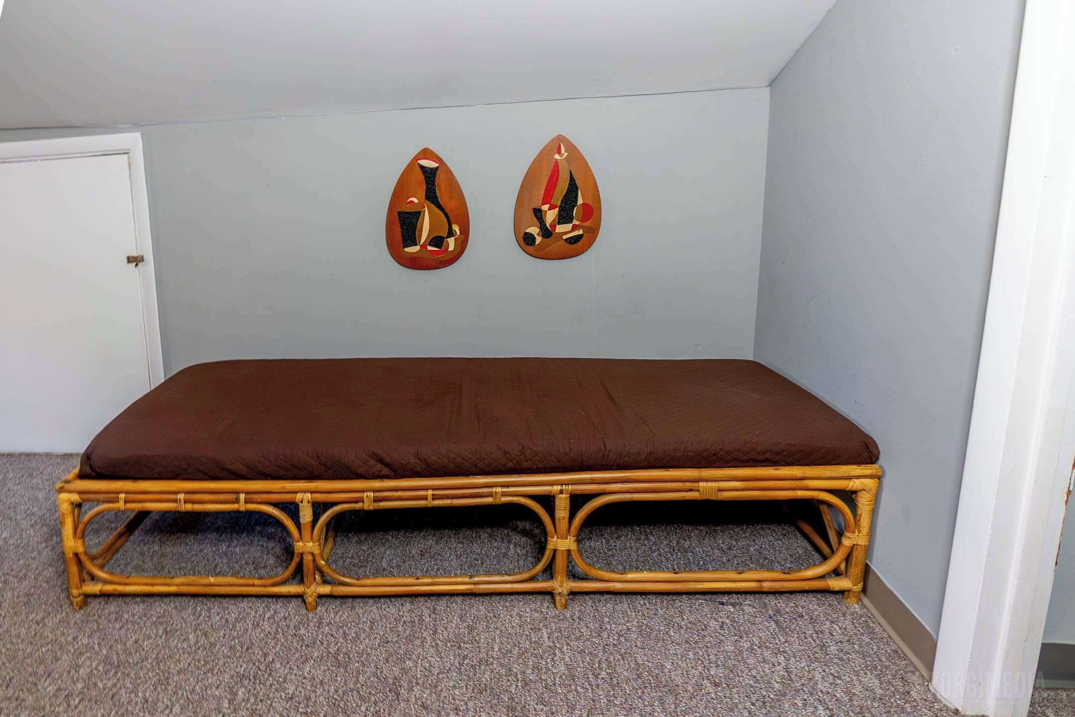 Une pièce comprenant un lit simple, une porte et deux éléments de décoration fixés au mur.