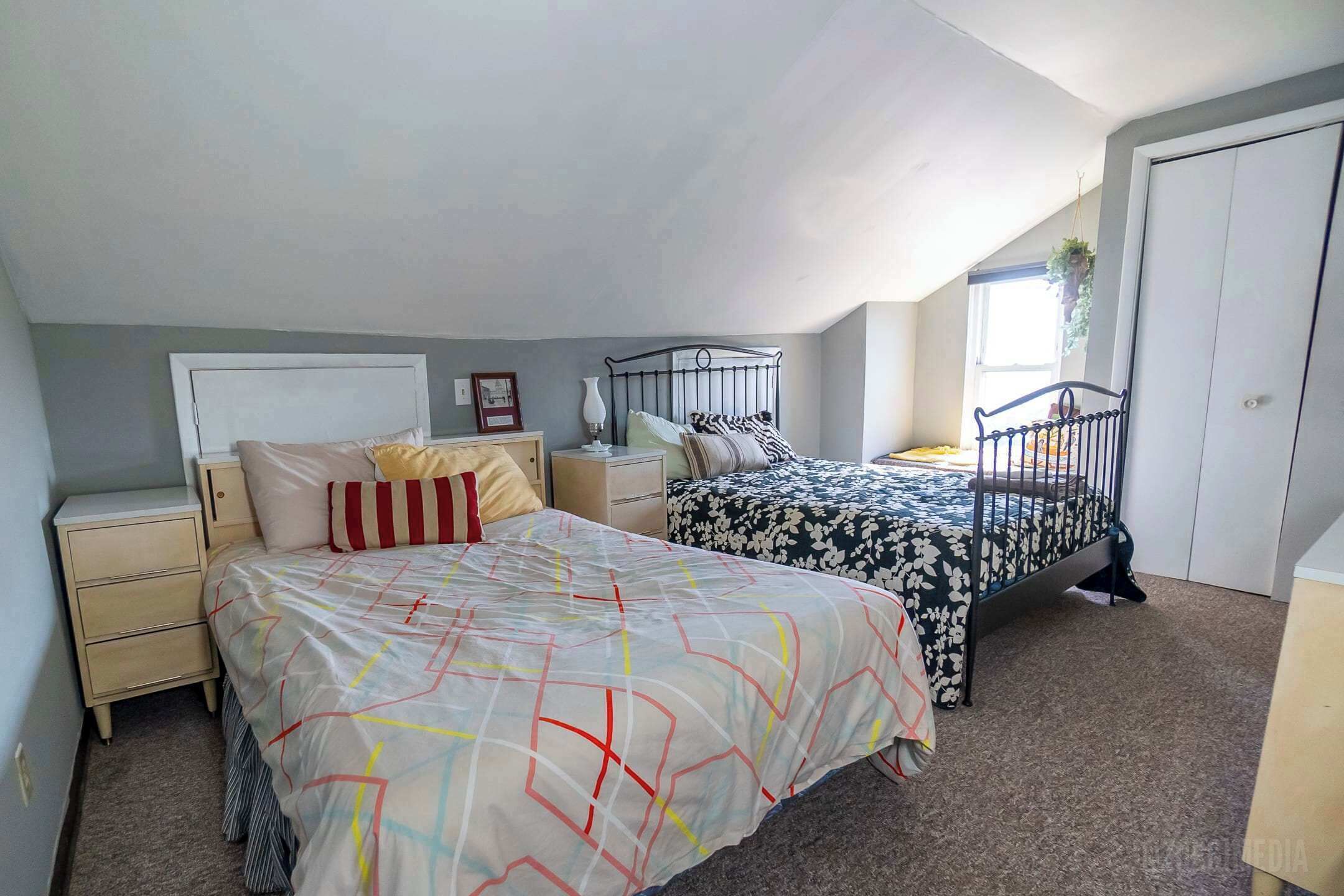 A bedroom with two beds, a window, and a door.