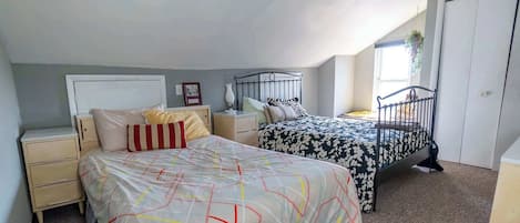 A bedroom with two beds, a window, and a door.