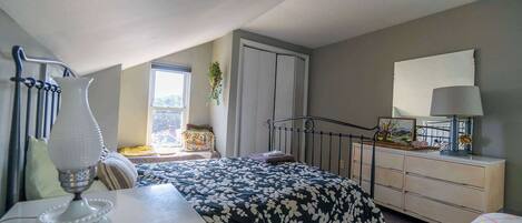 Un dormitorio con cama, cómoda, lámpara y ventana con vistas.
