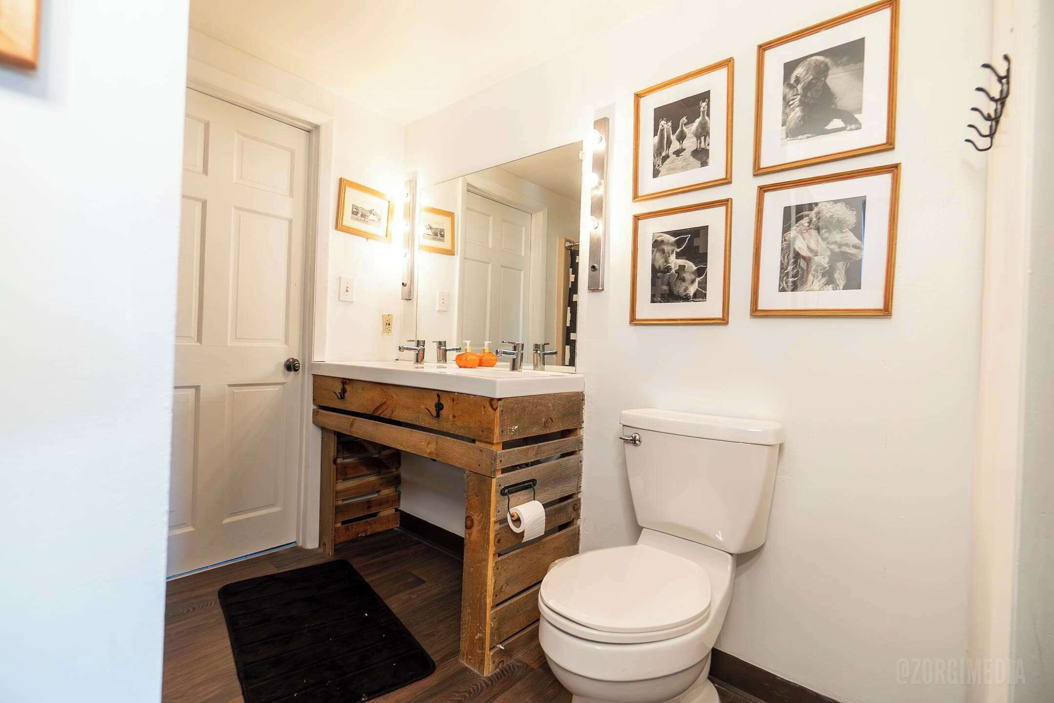 Ein Badezimmer mit einem Holzkosmetikschrank, einer Toilette und gerahmten Bildern an der Wand.