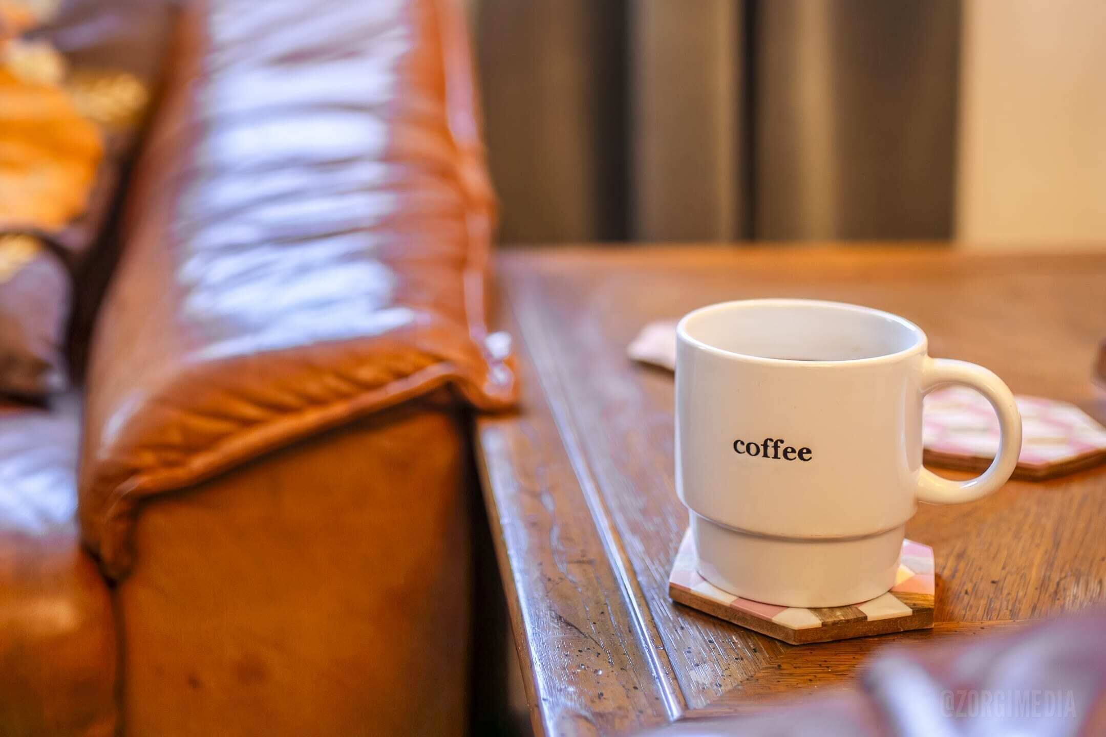 A white coffee mug with the word "coffee" on a wooden table.