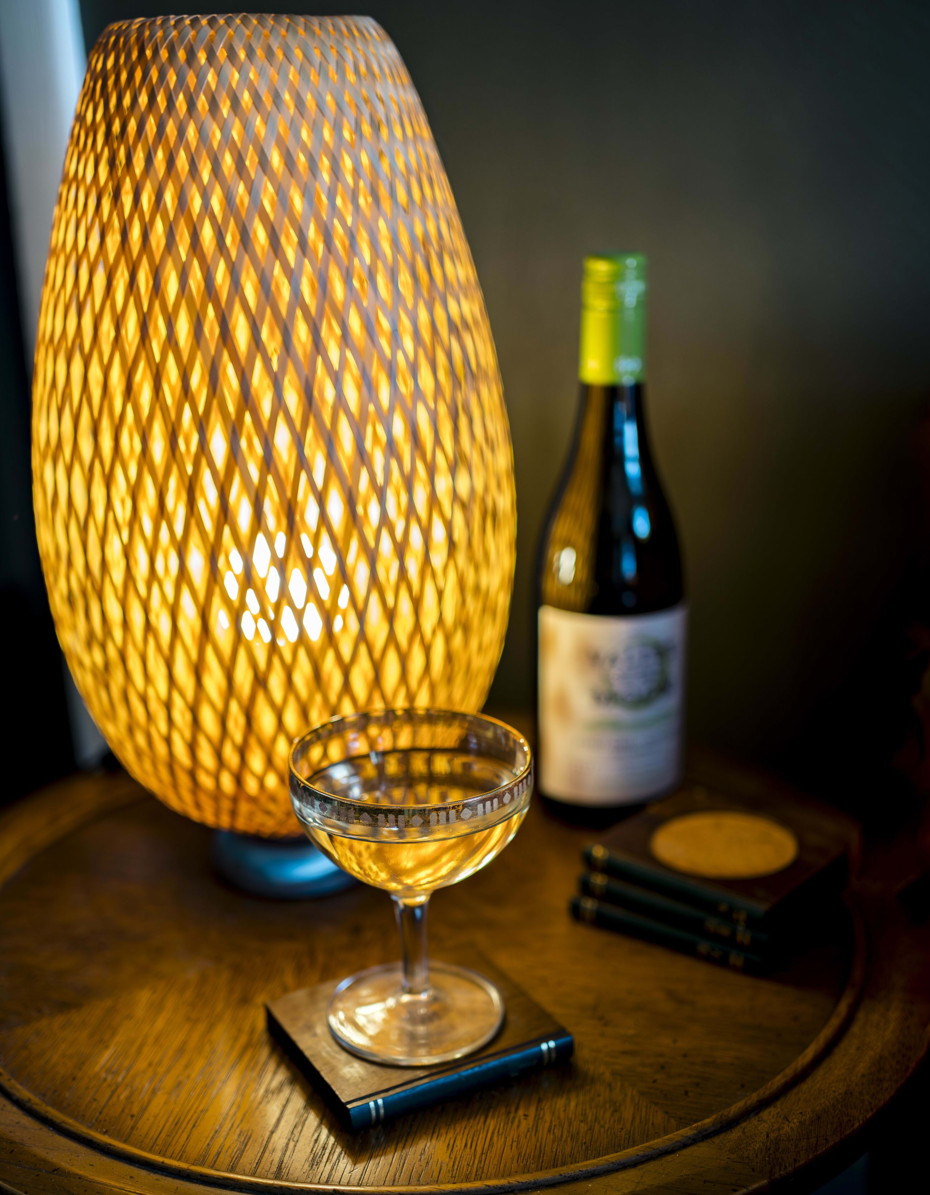Une table avec une bouteille de vin, un verre et une lampe décorative.