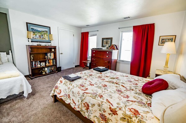 Une chambre à coucher comprenant un lit, une commode, une bibliothèque et un bureau.