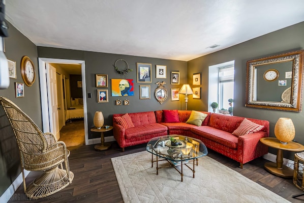 A living room with a red sectional sofa, a glass coffee table, and a wicker chair.