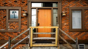 A brick building with a wooden door marked with the number 7, a wooden staircase, and two lantern-style wall lights. - Amazing Views- George Washington on Mt. Washington (Pittsburgh)