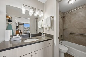 Un baño moderno con lavamanos doble, un espejo grande y cabina de ducha a ras de suelo.