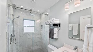Une salle de bain moderne avec une douche à parois de verre, des toilettes blanches et un lavabo avec un miroir.