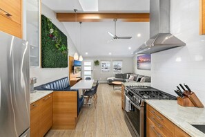A modern kitchen with a built-in stove, wooden cabinets, and a green wall feature. - Modern, Newly Renovated 2BR Apt in Heart of OB (San Diego)