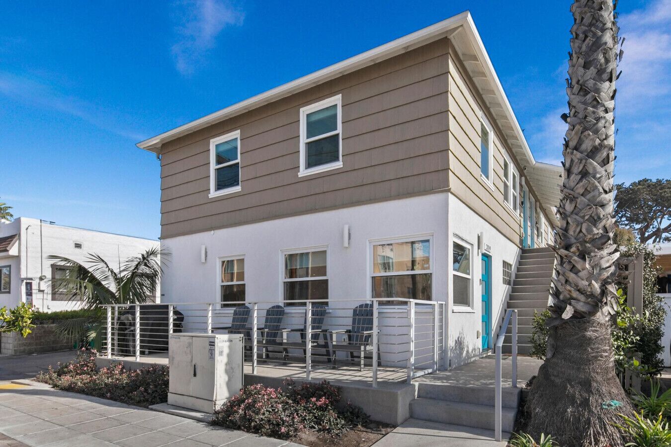 A two-story house with a flat roof, large windows, and a staircase leading to the upper floor.