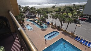 A pool area with multiple swimming pools, lounge chairs, and palm trees. - Caravelle 505 Ocean view Efficiency w/pools (Myrtle Beach)
