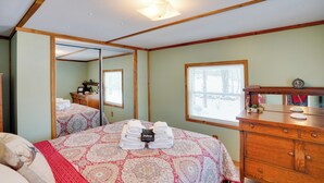 Un dormitorio con cama, cómoda, espejo y ventana.