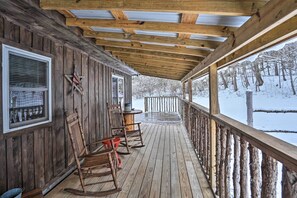 En träveranda med gungstolar och utsikt över ett snötäckt landskap.