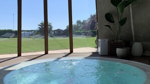 Un bain à remous avec vue sur une zone verdoyante et un bâtiment en arrière-plan.
