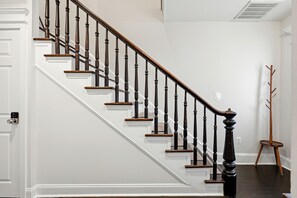 A staircase with wooden balusters and a handrail, leading to a landing with a coat rack. - Renovated 3B/3B Home | Downtown | Private Fire Pit (Leesburg)