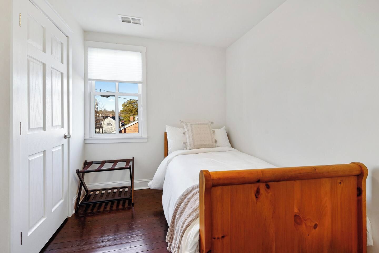 Un dormitorio con una cama de madera, una ventana con vistas y una puerta.