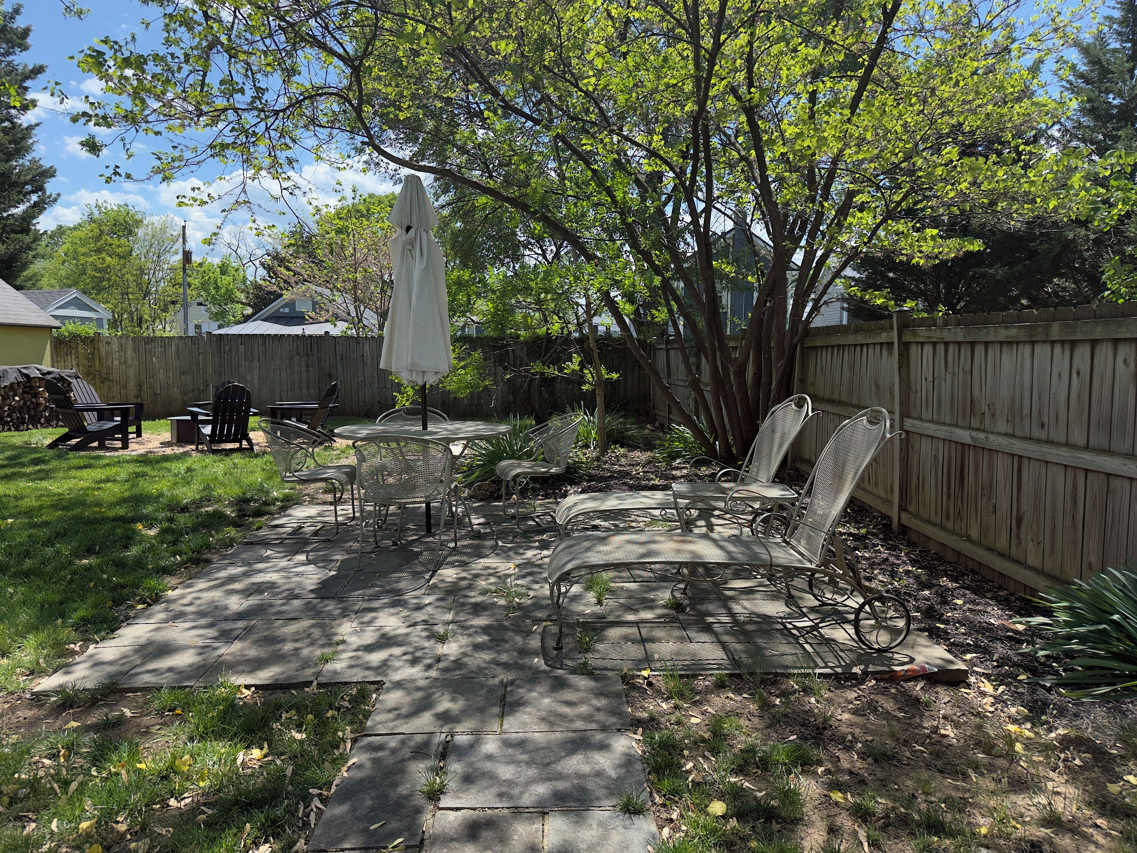 A backyard patio with a table, chairs, and an umbrella.