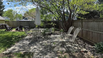 A backyard patio with a table, chairs, and an umbrella.