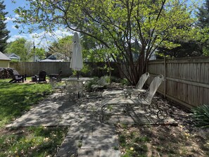 A backyard patio with a table, chairs, and an umbrella. - Renovated 3B/3B Home | Downtown | Private Fire Pit (Leesburg)