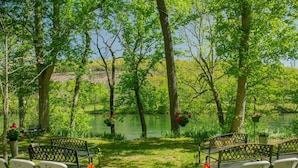 An outdoor seating area with chairs and tables, surrounded by trees and a body of water.