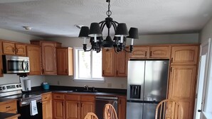 A kitchen with wooden cabinets, a stainless steel refrigerator, a microwave, and a dining table with chairs.