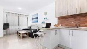 A modern kitchen with white cabinets, a brick backsplash, and a laptop on the counter.