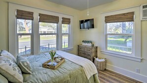 A bedroom with a large bed, a ceiling fan, a TV mounted on the wall, and a view of the outside. - Centrally Located House in Chico w/ Gas Grill (Chico)