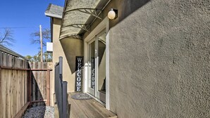 A wooden deck with a welcome mat leading to a house with a textured exterior wall and a metal railing. - Centrally Located House in Chico w/ Gas Grill (Chico)
