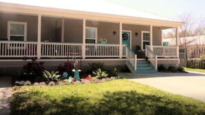 A two-story house with a covered porch, a front yard with plants, and a driveway.