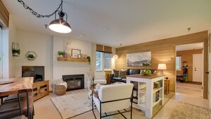 A modern living room with a fireplace, a TV, and a dining area. - Ski-In/Ski-Out Boyne Mountain Resort Rental! (Boyne Falls)