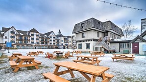 A snow-covered outdoor area with picnic tables and a building with a staircase. - Ski-In/Ski-Out Boyne Mountain Resort Rental! (Boyne Falls)