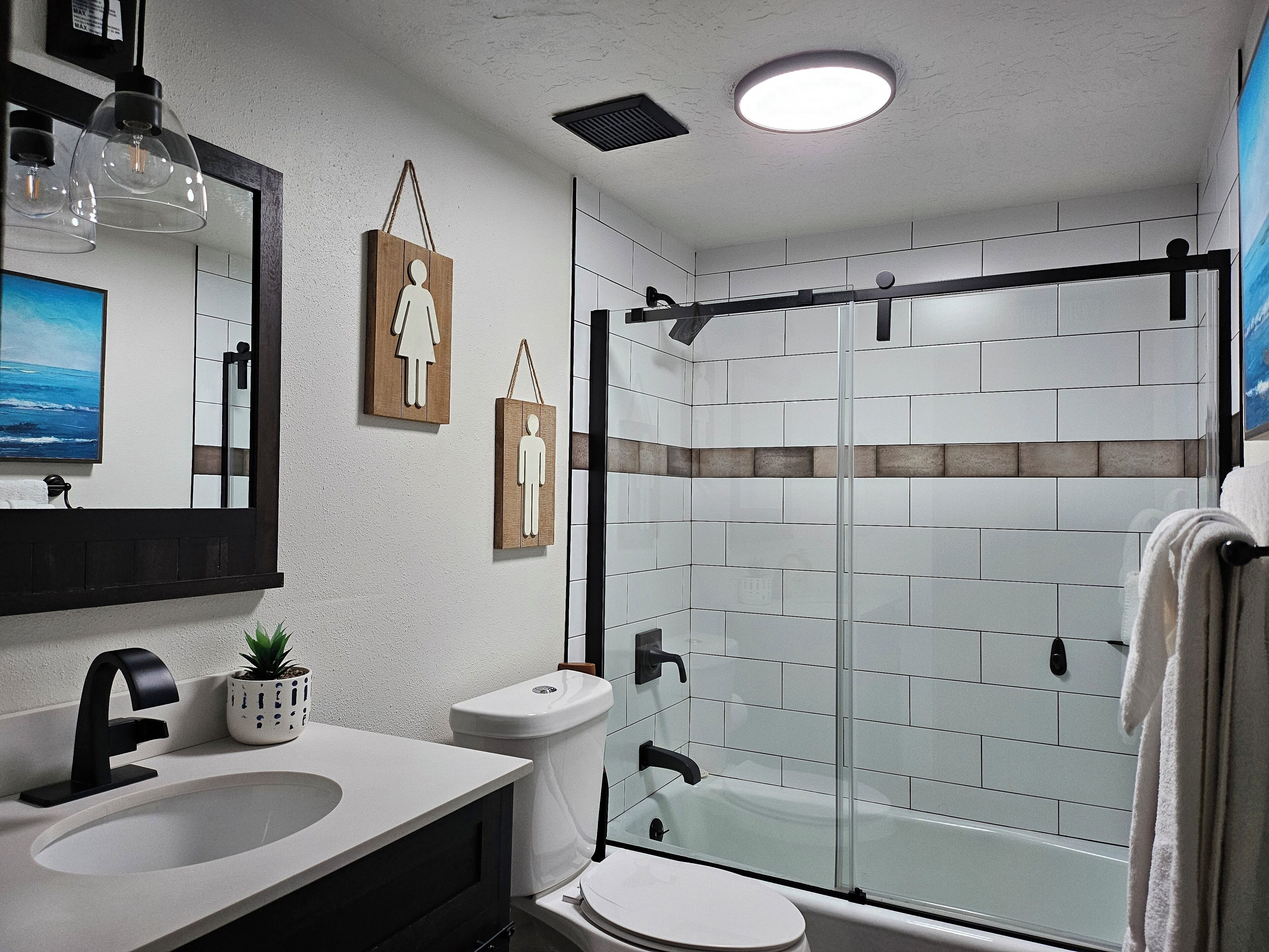 Un baño moderno con cabina de ducha de vidrio, un lavabo blanco y un inodoro.
